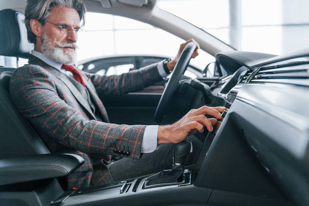 Side view of modern stylish senior man with grey hair that is in the modern car. - Fotoğraf, Görsel