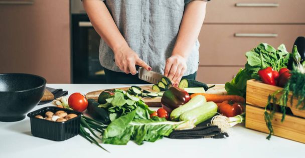 Foto ravvicinata delle mani della donna che tagliano verdure fresche su un tavolo da cucina - Foto, immagini
