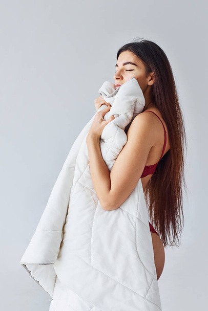 Woman covering her body by towel in the studio against white background. - Foto, immagini