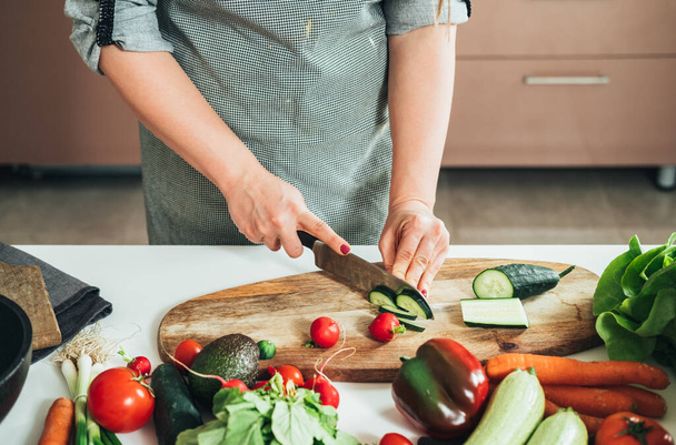 Close Up Photo of Woman Hands Friss zöldségek vágása a konyhaasztalnál. Magas látószögű kilátás egy névtelen háziasszony, hogy egészséges ebéd friss színes zöldségek otthon. - Fotó, kép