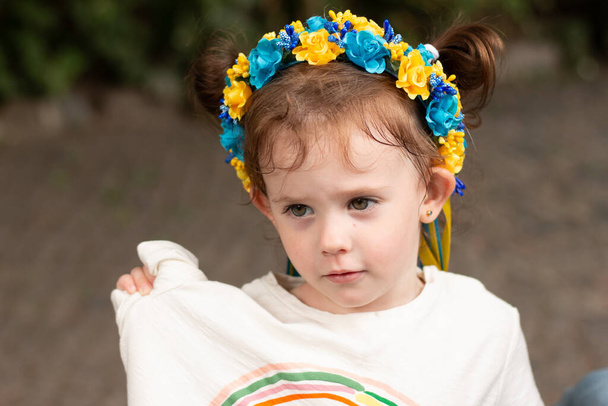 Pequena menina pré-escolar ruiva com tranças em decoração popular ucraniana nacional grinalda ao ar livre - Foto, Imagem