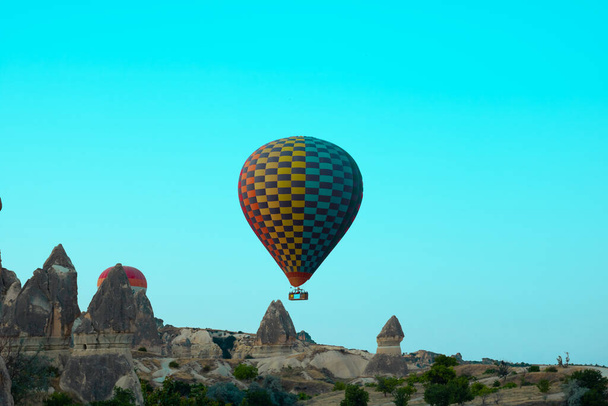 Hot air balloon taking off and fairy chimneys in Cappadocia. Famous activity of Cappadocia. Hot air balloon tour in Goreme. Tourism in Turkey. - Foto, Imagem