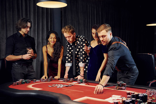 People in elegant clothes standing and playing poker in casino together. - Valokuva, kuva
