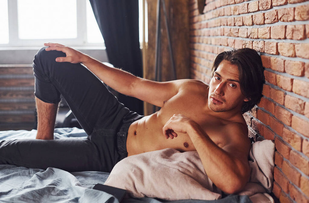 Póló nélküli szexi férfi pihenni egyedül a hálószobában reggelente. - Fotó, kép