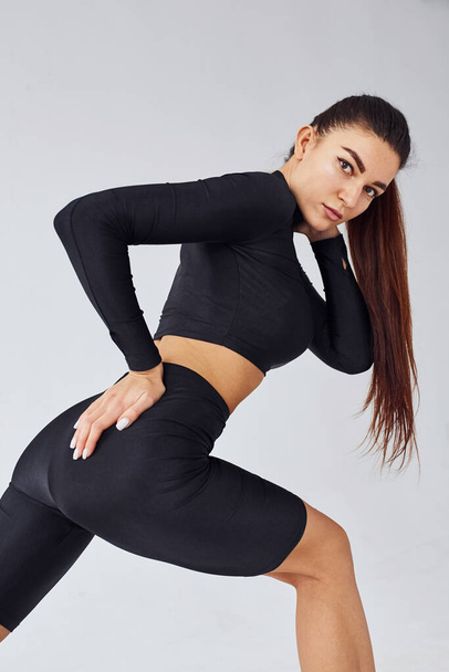 Twerk dancing. Sportive woman in black clothes in the studio against white background. - Photo, image