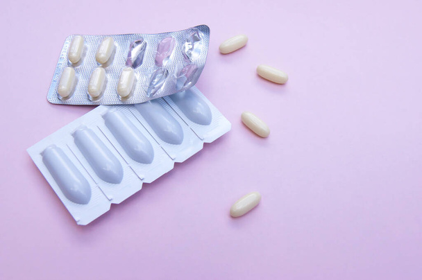 Farmaci ginecologici per la salute delle donne in forma di supposte, capsule su sfondo rosa. Trattamento delle infezioni vulvovaginali. Vista dall'alto. - Foto, immagini