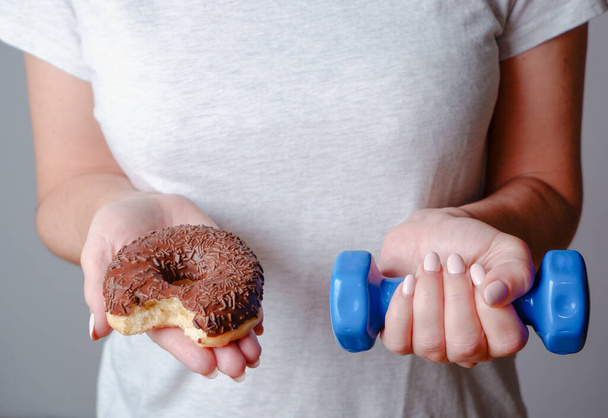 Diet. Woman Holding Donut and Dumbbell. Sweets Are Unhealthy Junk Food. - Fotoğraf, Görsel