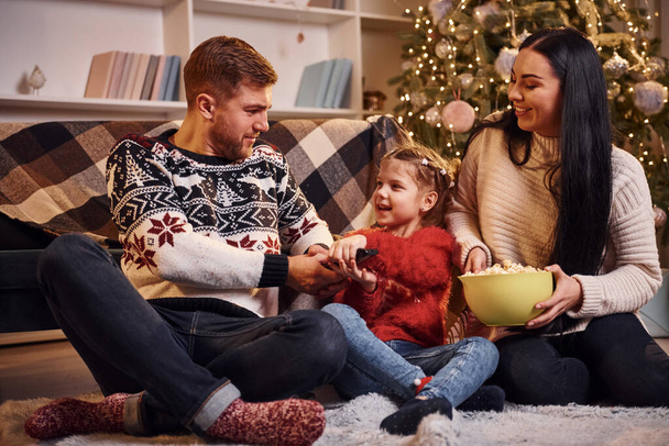 Happy family indoors in christmas decorated room celebrating new year with popcorn. - Fotoğraf, Görsel