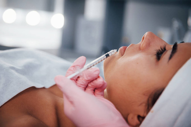 Close up view of woman that lying down in spa salon and have injection by the syringe into her face skin. - Foto, Imagen