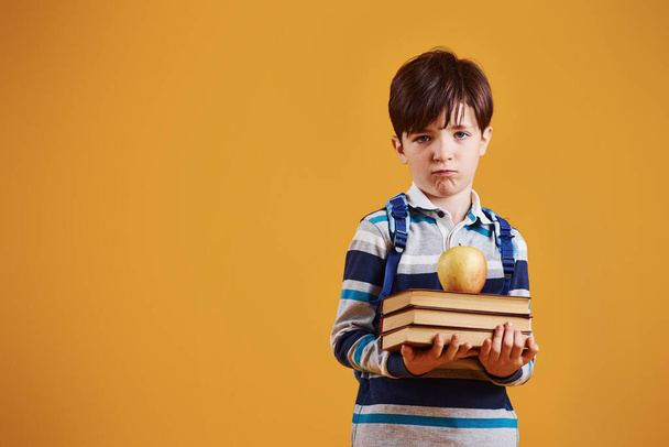 Portrait of young smart schooler in the studio against yellow background. - Photo, image