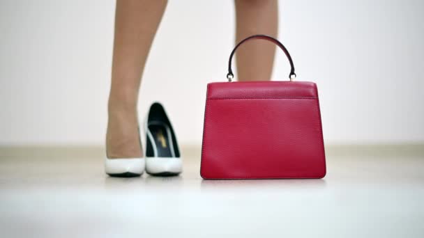 Женщина надевает белые туфли и красную сумочку - Кадры, видео