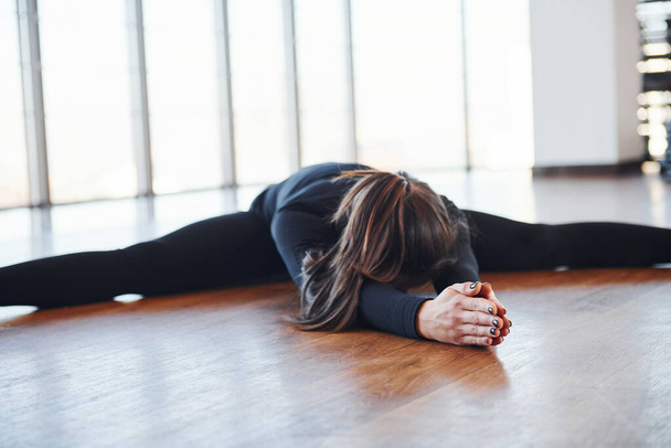 Sporty woman in black sportswear lying down on the floor by doing stretching. - Foto, immagini