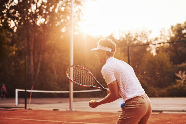 Young tennis player in sportive clothes is on the court outdoors. - Foto, Bild