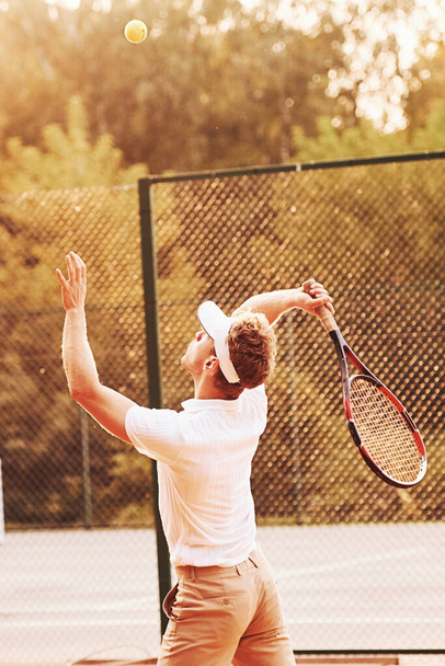 Young tennis player in sportive clothes is on the court outdoors. - Fotó, kép