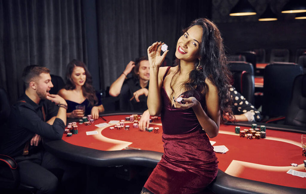 Portrait of beautiful woman. Group of elegant young people that playing poker in casino together. - Foto, Imagem