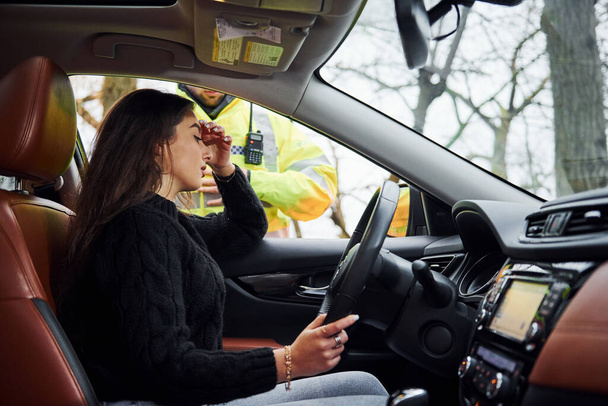 Girls feels bad. Male police officer in green uniform checking vehicle on the road. - Φωτογραφία, εικόνα