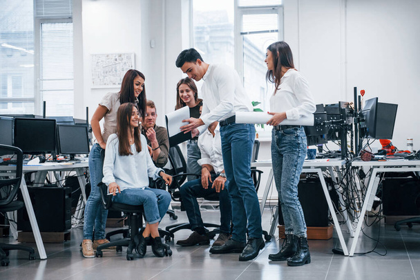 Skupina mladých podnikatelů, kteří stojí a sedí a pracují v kanceláři. - Fotografie, Obrázek