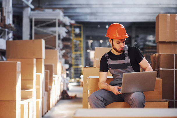 Storage worker in uniform and modern laptop in hands checks production. - Foto, Imagem