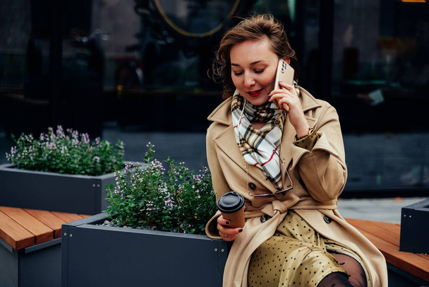 Beautiful business woman wearing beige coat talking on mobile phone - Zdjęcie, obraz
