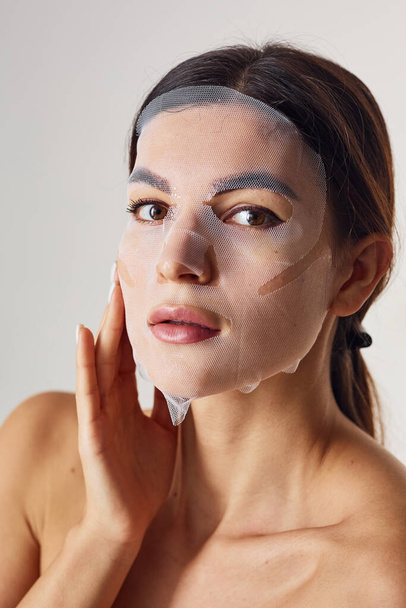 Portrait of woman is in the studio against white background with beauty mask on face. - Foto, immagini