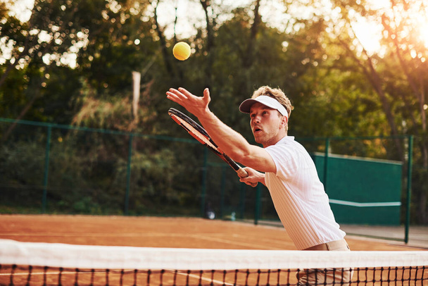 Young tennis player in sportive clothes is on the court outdoors. - Photo, image