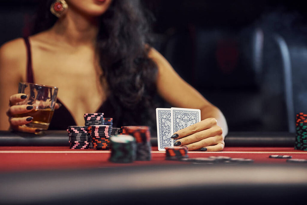 Woman in elegant clothes sits in cassino by table and plays poker game. - Photo, image