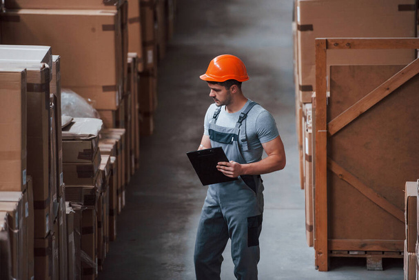Storage worker in uniform and notepad in hands checks production. - Foto, imagen
