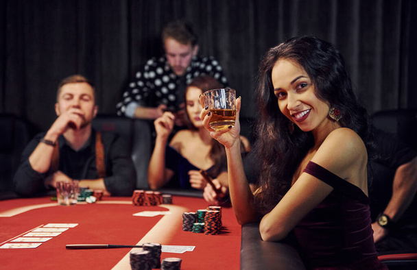 Portrait of beautiful woman. Group of elegant young people that playing poker in casino together. - Foto, Imagem
