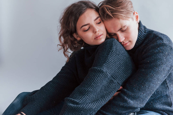 Cute young couple embracing each other indoors in the studio. - Photo, image