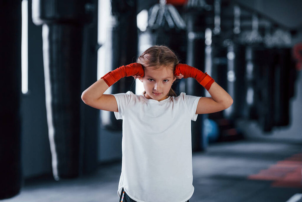 Portrait of young little girl in sportive wear that is in the gym have exercise day. Conception of boxing. - Фото, изображение