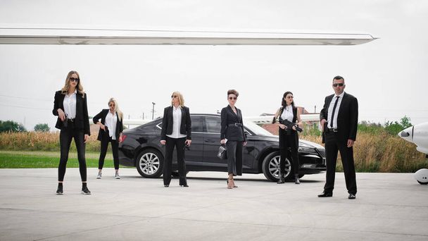 Professional team of female and male bodyguards protect famous VIP celebrity public person. Close security protection. Police agent in civilian black suit - Foto, imagen
