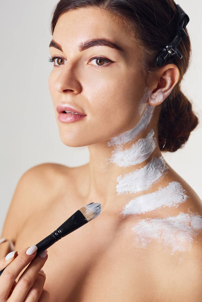 Painting body. Naked woman is in the studio against white background. - Valokuva, kuva