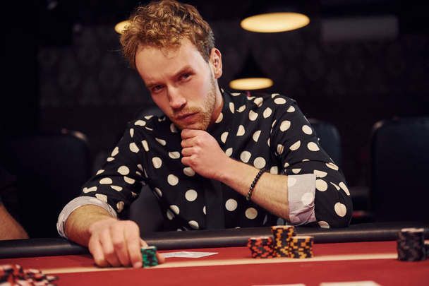 Eleganter junger Mann sitzt im Casino und spielt Pokerspiel. - Foto, Bild
