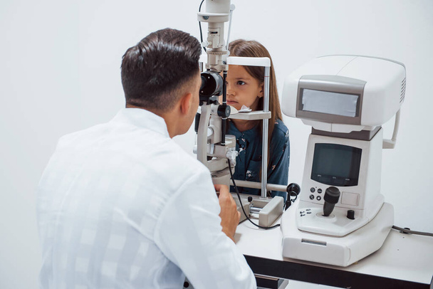 Young ophthalmologist is with little female visitor in the clinic. - Foto, immagini