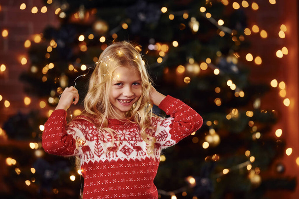 Linda niña en cerca del árbol de Navidad en el interior celebrando el año nuevo. - Foto, Imagen