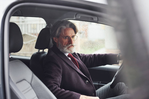 Fashionable senior man in elegant clothes is in the modern car. - Photo, Image