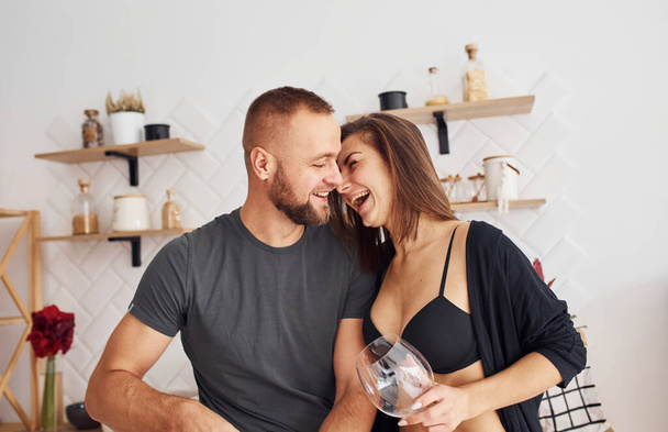 Woman in sexy black lingerie with her husband on the kitchen. - Zdjęcie, obraz