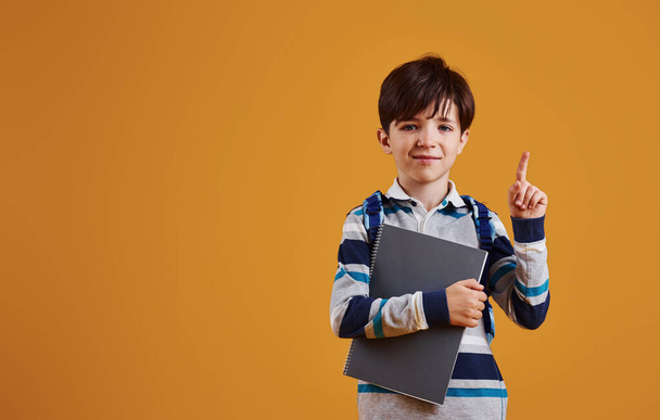 Portrait of young smart schooler in the studio against yellow background. - Foto, Imagem