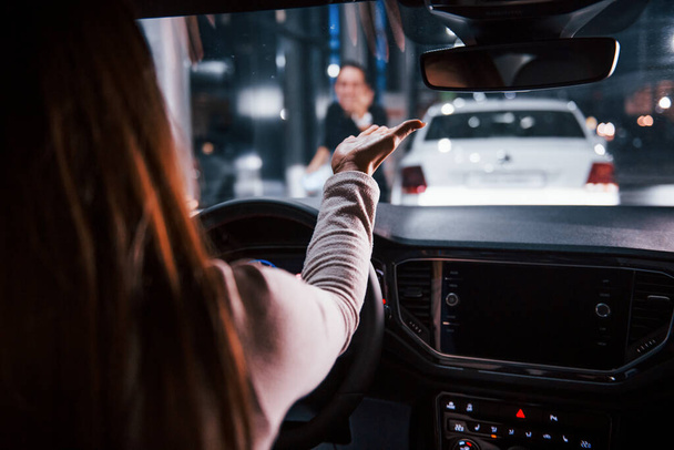 Mladá žena je uvnitř zbrusu nové moderní automobil drží ruku před ní na dívku. - Fotografie, Obrázek