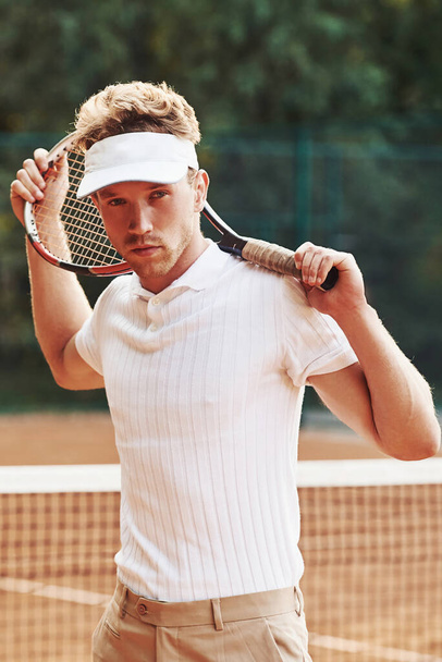 Posing for a camera. Young tennis player in sportive clothes is on the court outdoors. - Foto, Imagem