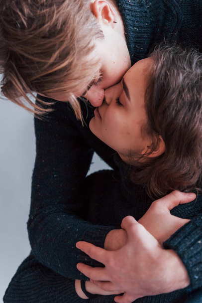 Cute young couple kissing each other indoors in the studio. - 写真・画像
