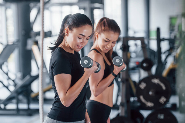 Female personal trainer helping woman doing exercises in the gym. - Photo, Image