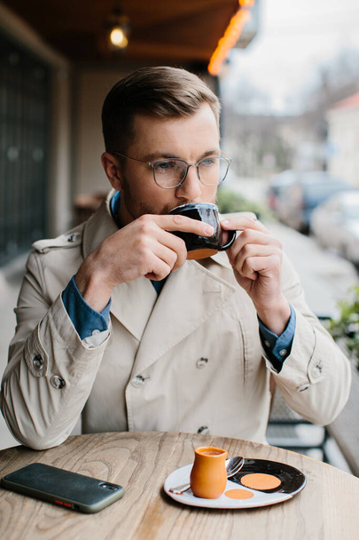 Junger Mann trinkt Kaffee in einem Café im Freien. - Foto, Bild