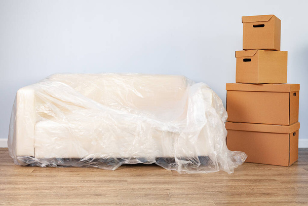 Packed household stuff in boxes and packed sofa for moving - Φωτογραφία, εικόνα