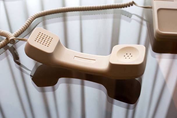 Гарнітура стаціонарного телефону на скляному столі
 - Фото, зображення
