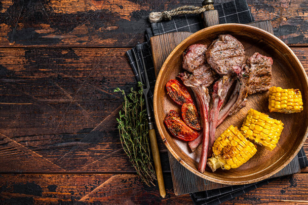 BBQ Roasted chops steaks of lamb, mutton in a wooden plate. Dark wooden background. Top view. Copy space - Foto, Imagem
