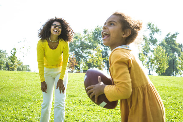 Beautiful happy african american family bonding at the park - Black family having fun outdoors, parents and kids playing football - Photo, image