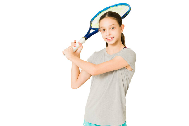 Ritratto di una giovane ragazza caucasica felice che si gode una partita di tennis e pronta a colpire la palla  - Foto, immagini