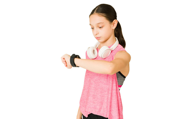Resultados y objetivos de fitness. Chica atlética comprobando el tiempo en su smartwatch y contando las calorías en una aplicación - Foto, Imagen