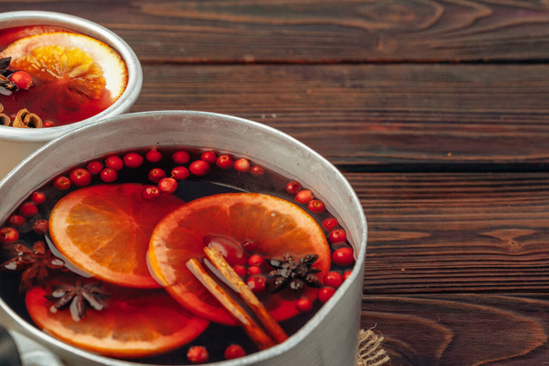 Close up of mulled wine cup with spices and berries on grey table - Foto, Bild